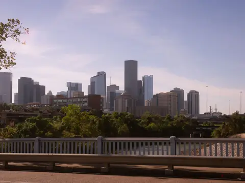 Downtown Houston's skyline above green trees on a clear day