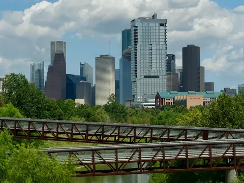 The Houston skyline over a bridge and the calm water of Buffalo Bayou