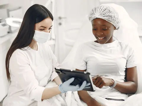 A provider and a client looking at a tablet together in a bright consultation room