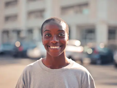 A smiling woman outdoors on a sunny street